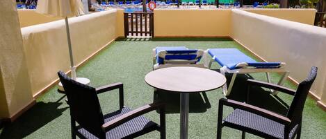 En takterrass med en pool, solstolar och ett bord.