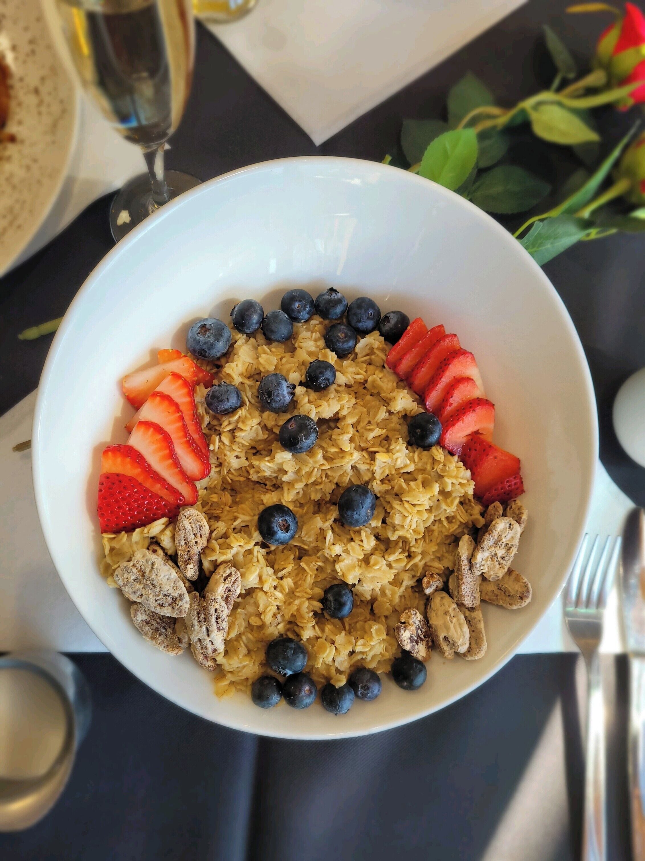 Un bol de porridge garni de myrtilles, de fraises et de noix, posé sur une table.