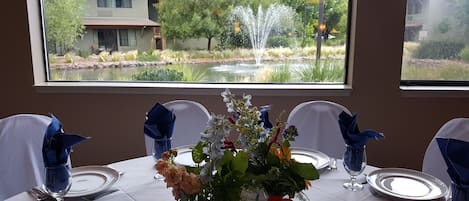 Een eettafel gedekt voor vier personen, met uitzicht op een fontein en groen.