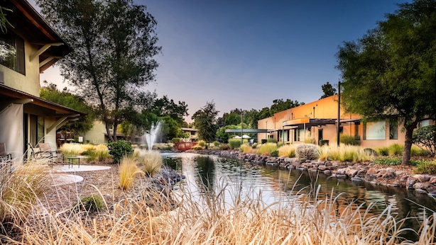A serene outdoor area with a pond, seating, and modern buildings. - Gaia Hotel & Spa Redding, an Ascend Collection Hotel (Anderson)