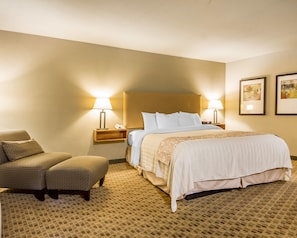 Une chambre d’hôtel avec un lit, deux lampes de chevet, une chaise et une table de chevet.