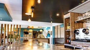 A modern bar area with a polished marble countertop, hanging pendant lights, and a Nespresso coffee machine. - Hôtel ibis Styles Marennes Oleron (Marennes-Hiers-Brouage)