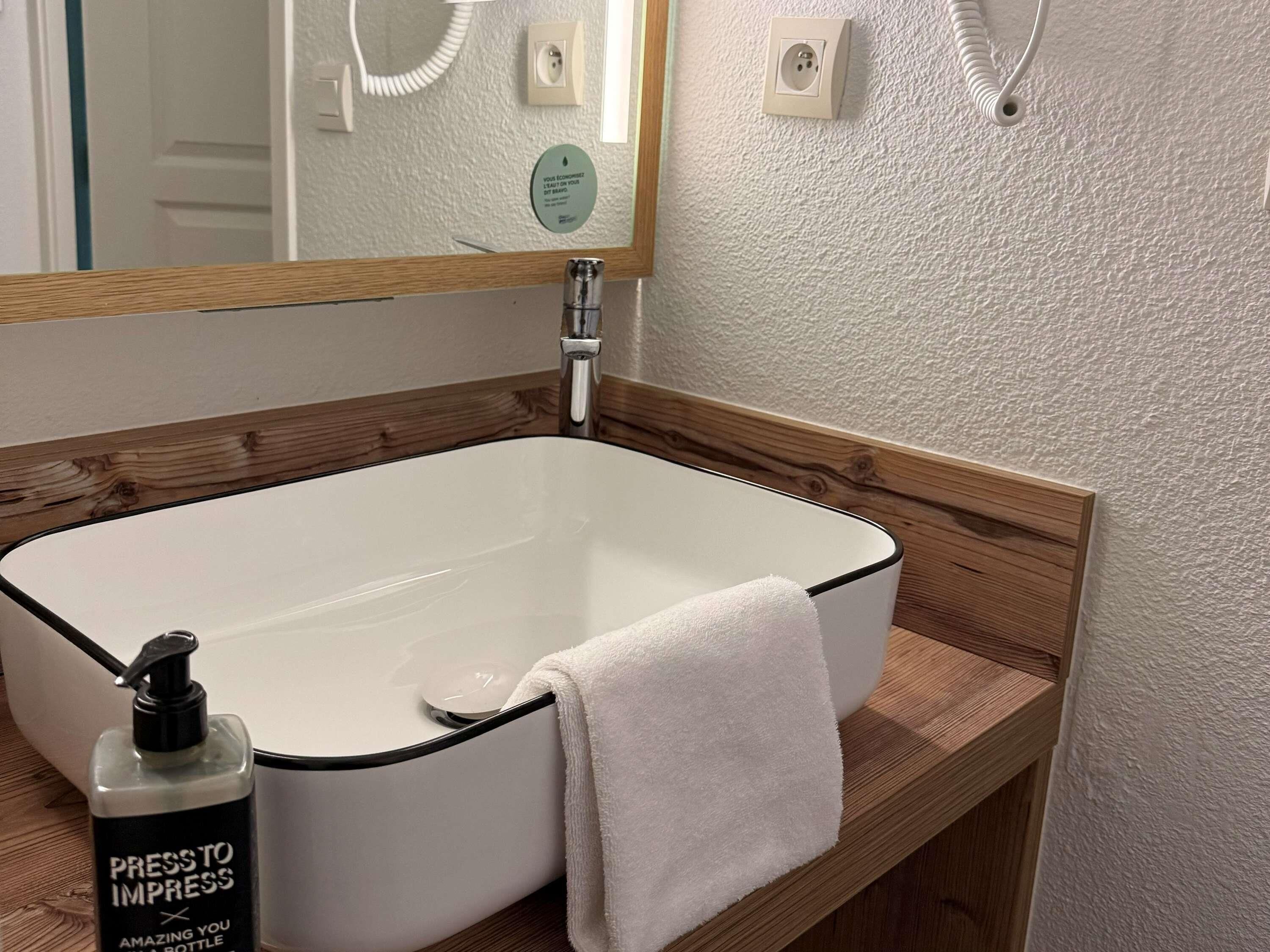 Ein Badezimmer mit einem weißen Waschbecken, einer Holzauskleidung und einem Spiegel darüber.