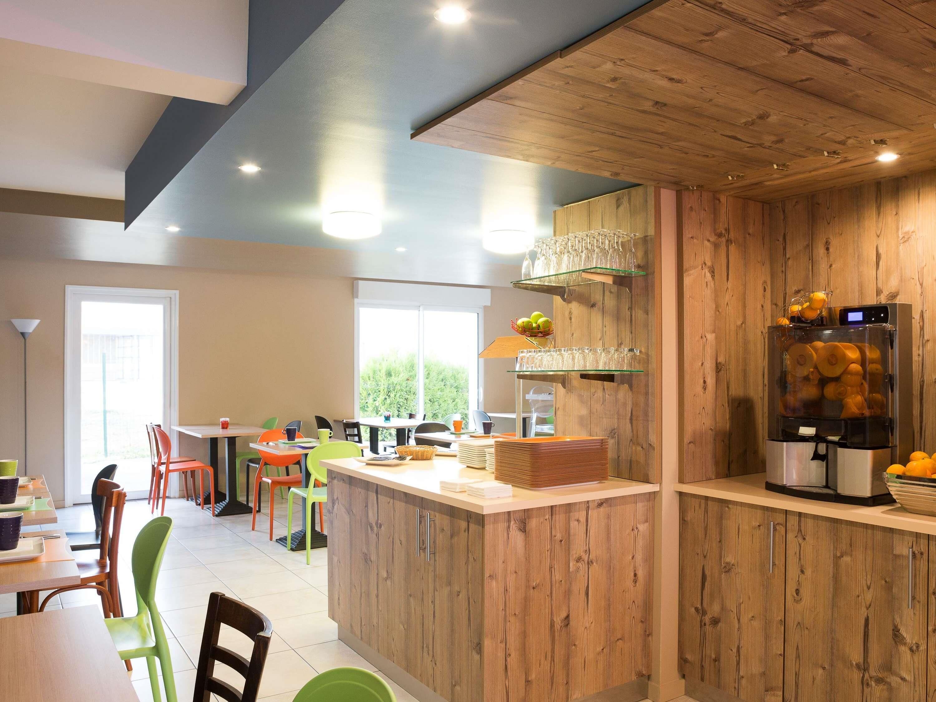 Une cuisine moderne dotée de meubles en bois, d’un îlot central et d’un distributeur intégré pour les fruits et légumes.