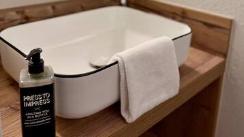 A bathroom with a white sink, a mirror, a towel, and a bottle of hand soap.