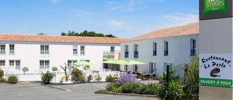 Un hotel con fachada blanca, techo de tejas y un cartel que dice 'ibis Styles Hotels'.