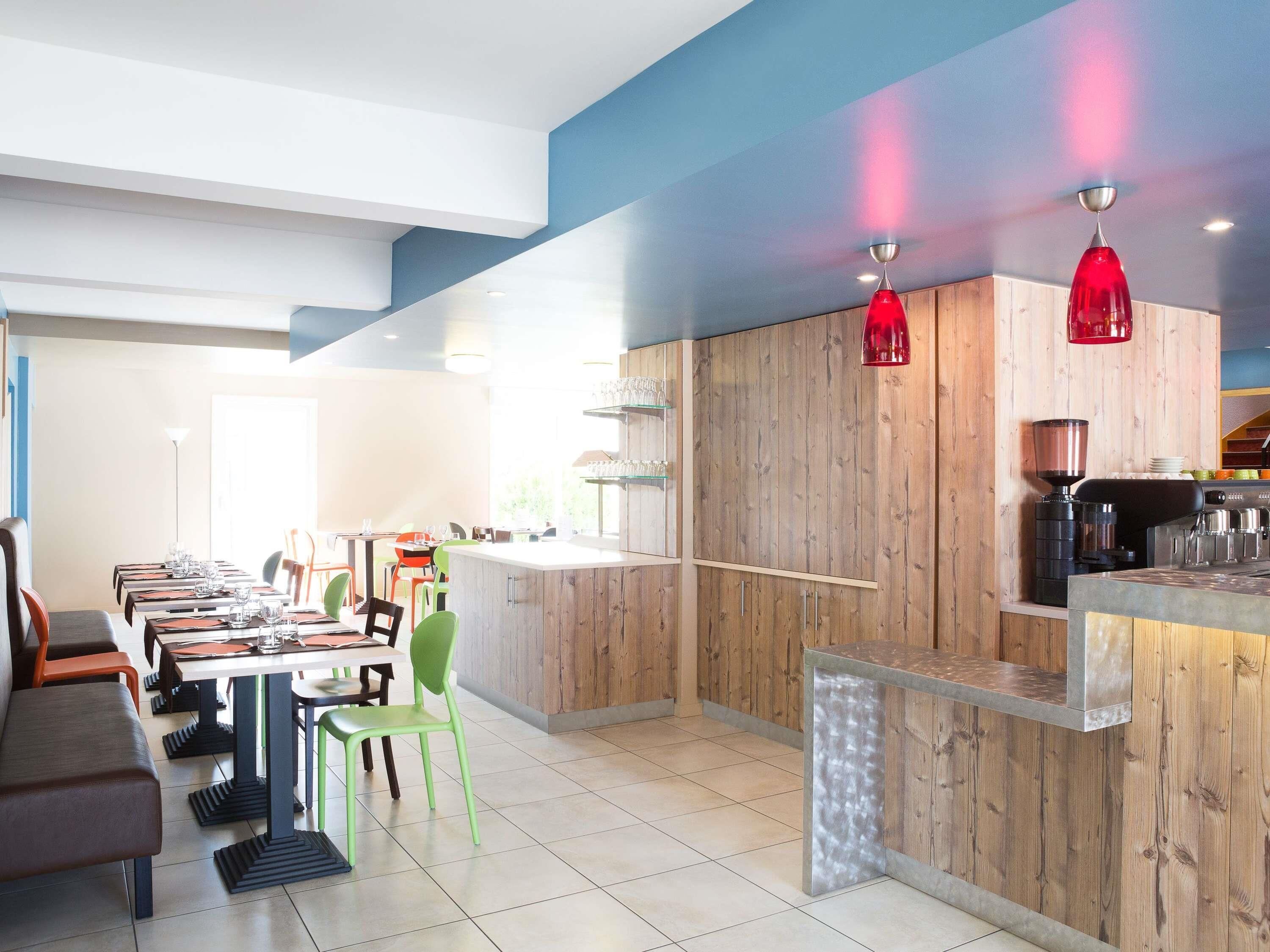 Un restaurant moderne avec des murs lambrés, un bar et des suspensions rouges.