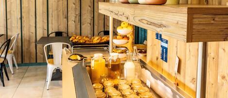 A breakfast bar with jars of honey, a variety of bowls, and a plant on the wall.