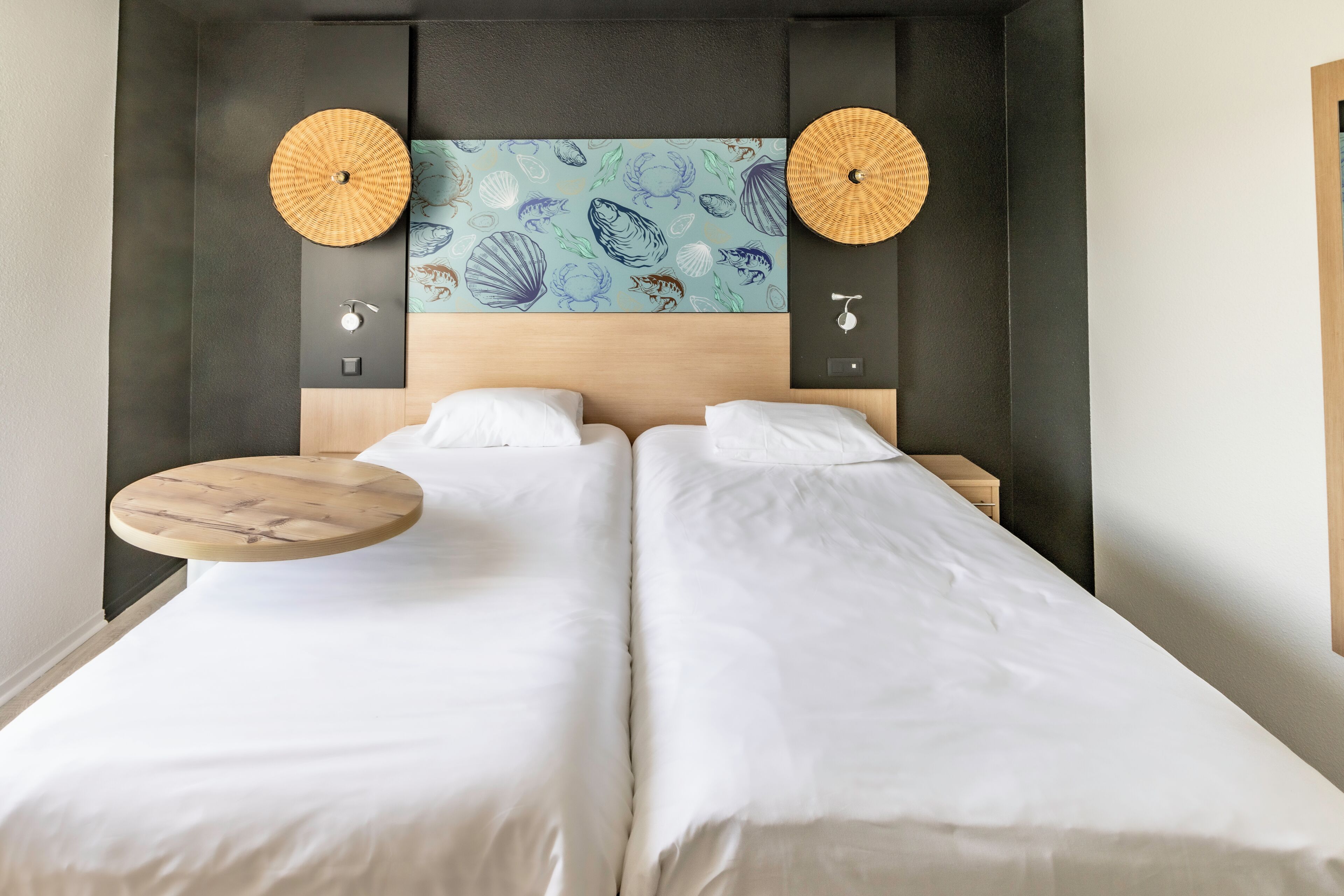 Een tweepersoonsbed met hoofdeinde, twee nachtkastjes en een aan de muur bevestigd kunstwerk.