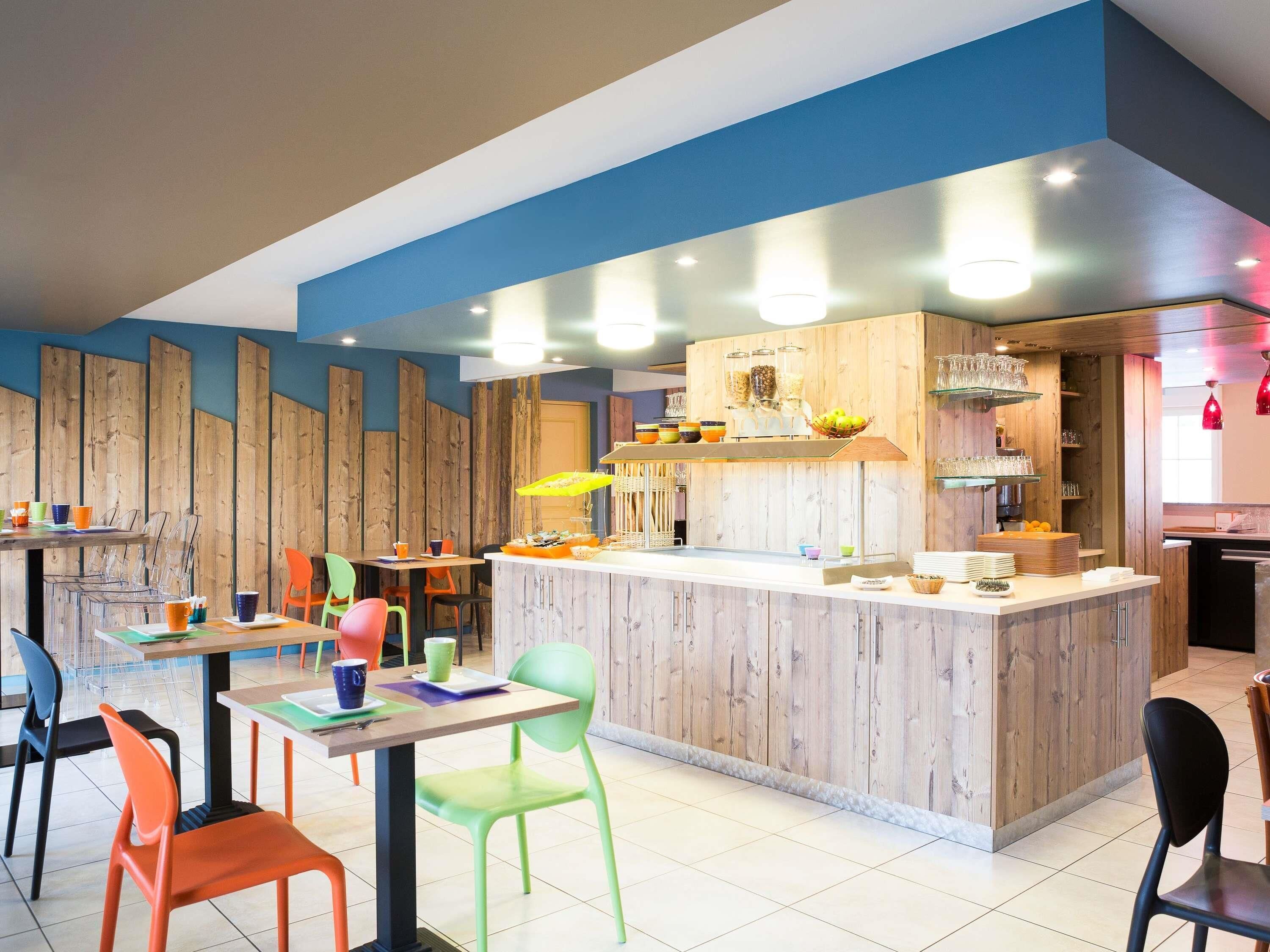 Een modern café met een houten toonbank, transparante plastic stoelen en een blauwe accentmuur.