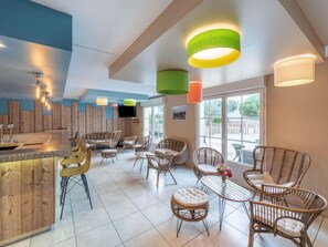 Un interior moderno con una zona de bar, muebles de mimbre y ventanas amplias.