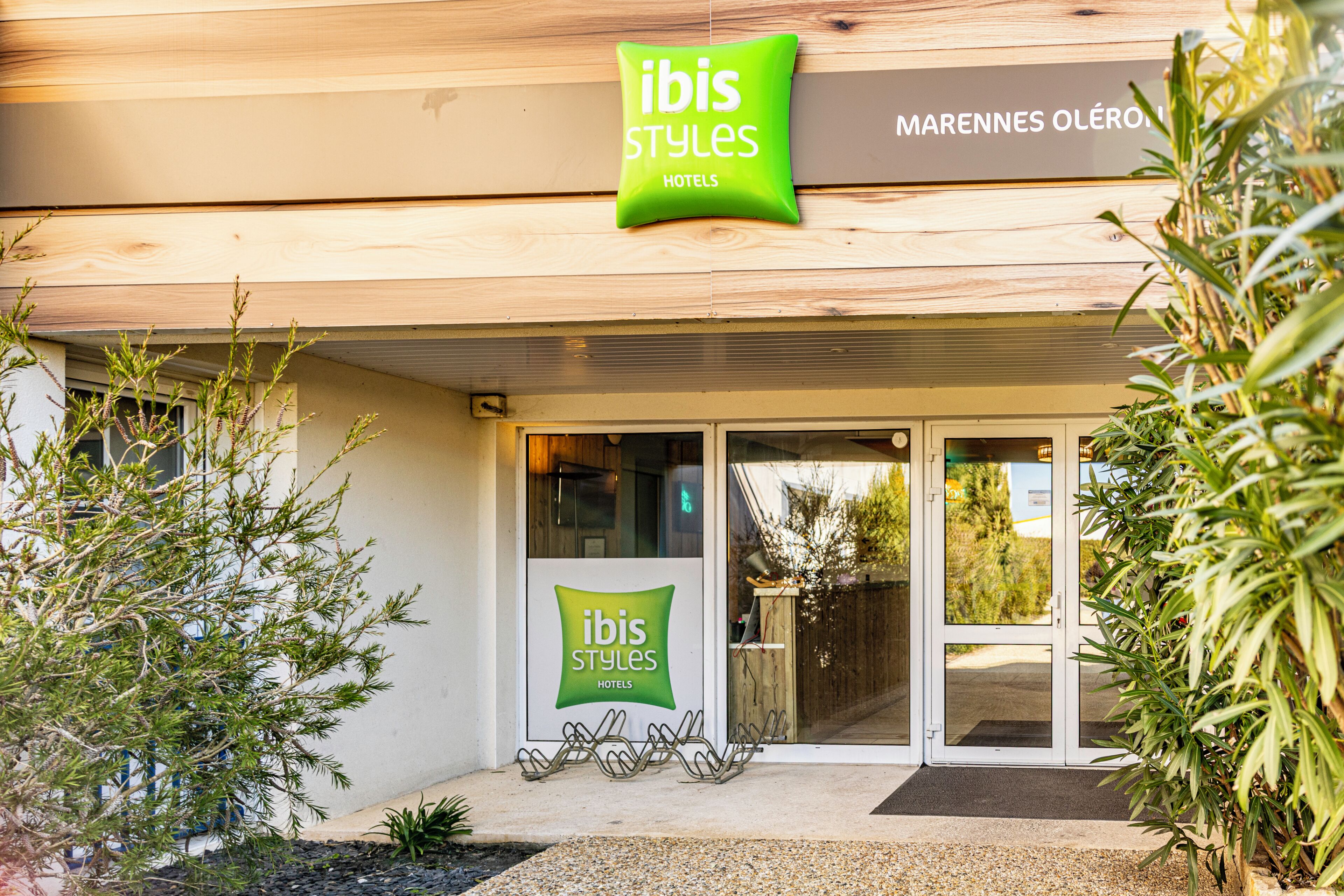 A hotel entrance with a sign reading 'ibis Styles Hotels' and a wooden facade.