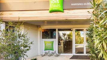 A hotel entrance with a sign reading 'ibis Styles Hotels' and a wooden facade.