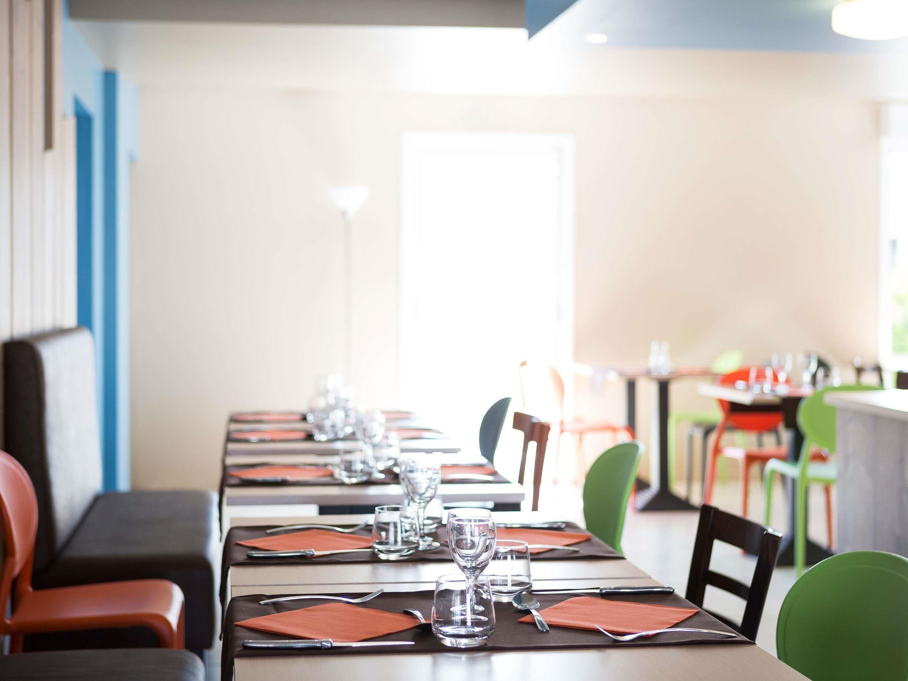 A restaurant with long tables set for dining, chairs, and a bright interior.
