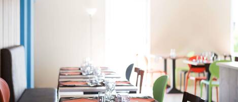 A restaurant with long tables set for dining, chairs, and a bright interior.