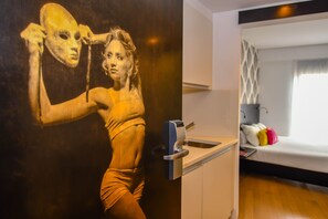 Quarto com cama, pia e dispensador de toalhas na parede.
