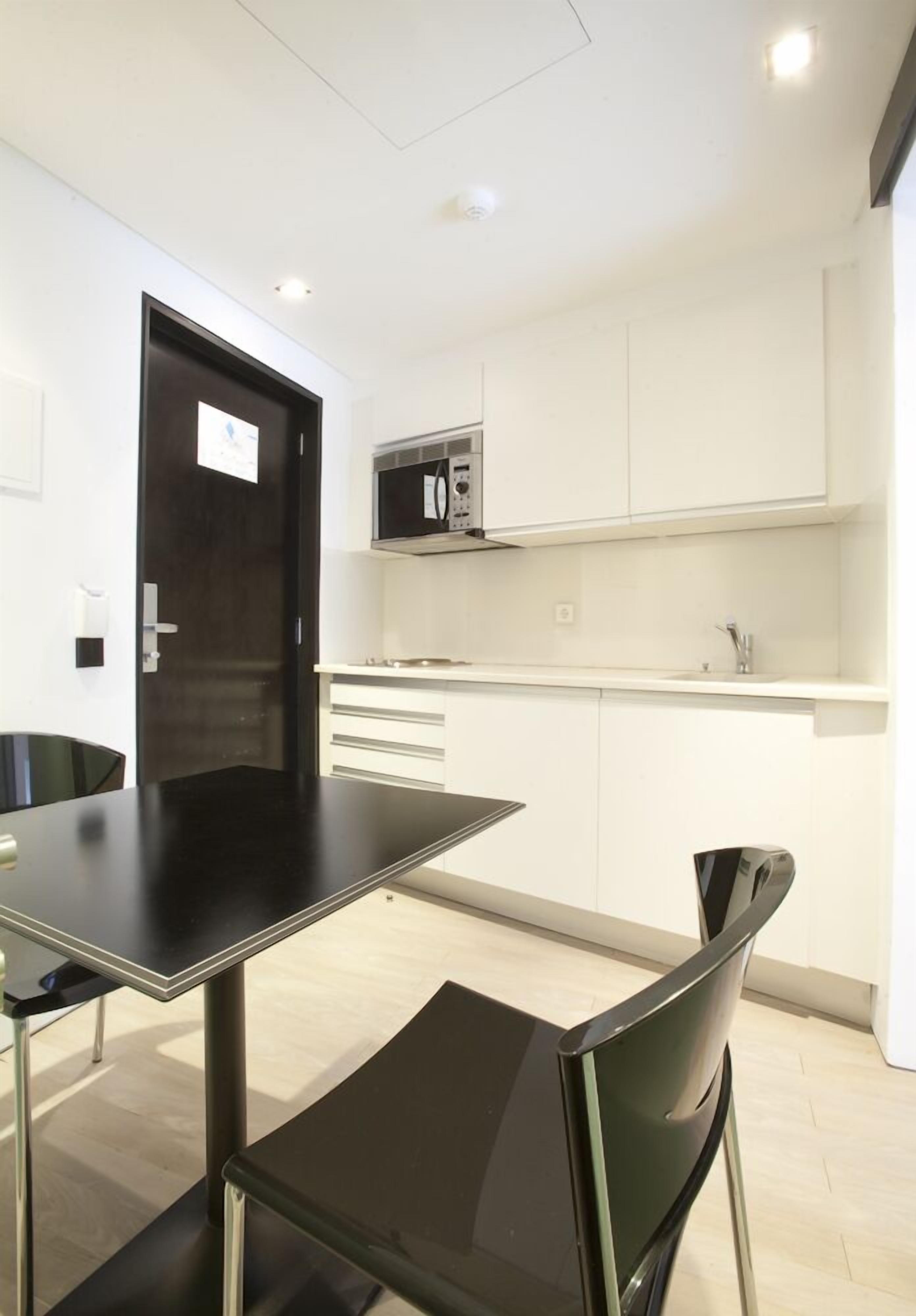 A modern kitchen with white cabinets, a black countertop, and a microwave.