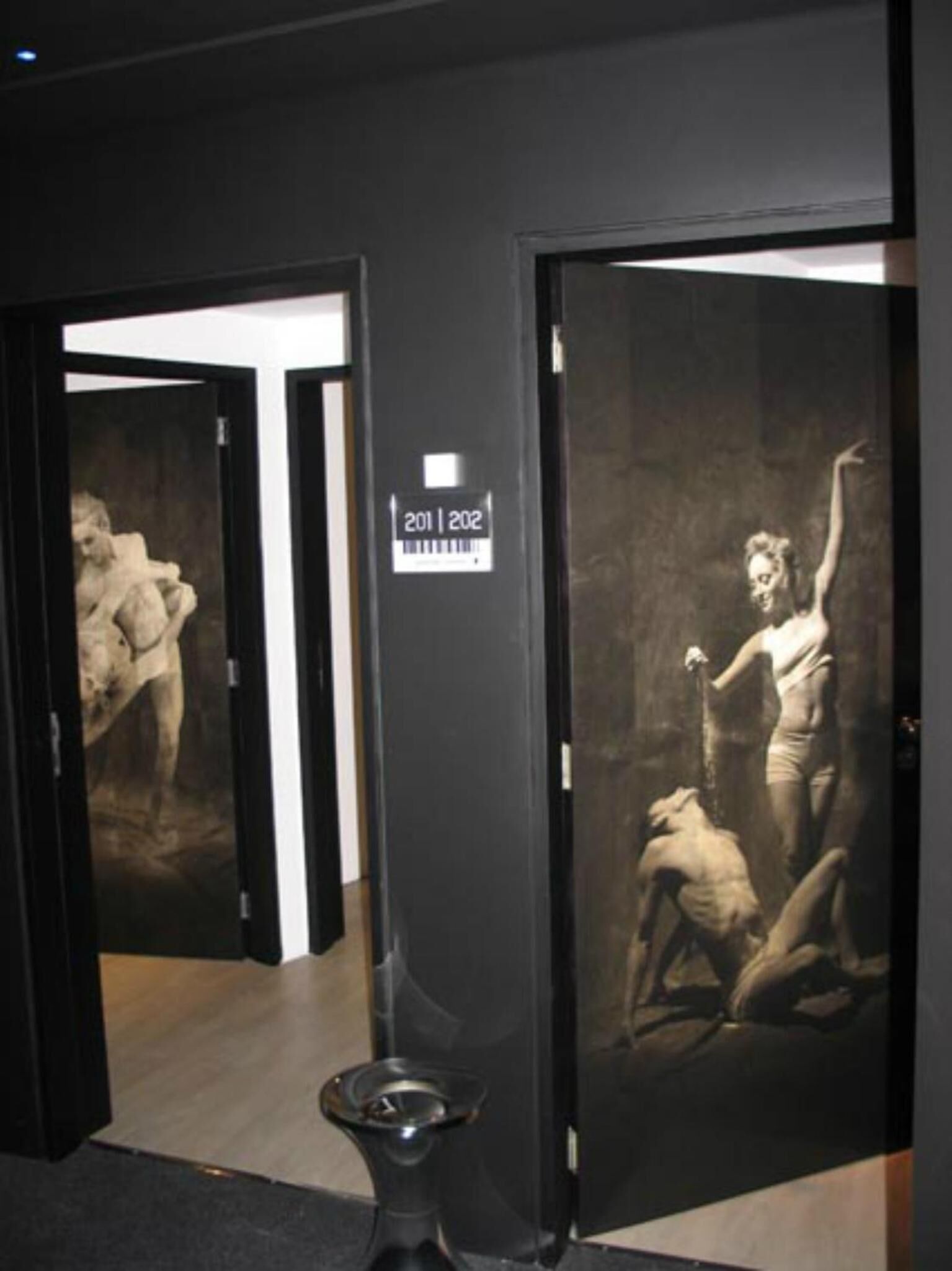 A hallway with doors leading to rooms, each with a numbered sign.