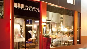 Un hotel llamado "Funchald Design" con una fachada moderna, ventanas amplias y una maceta roja en el exterior.