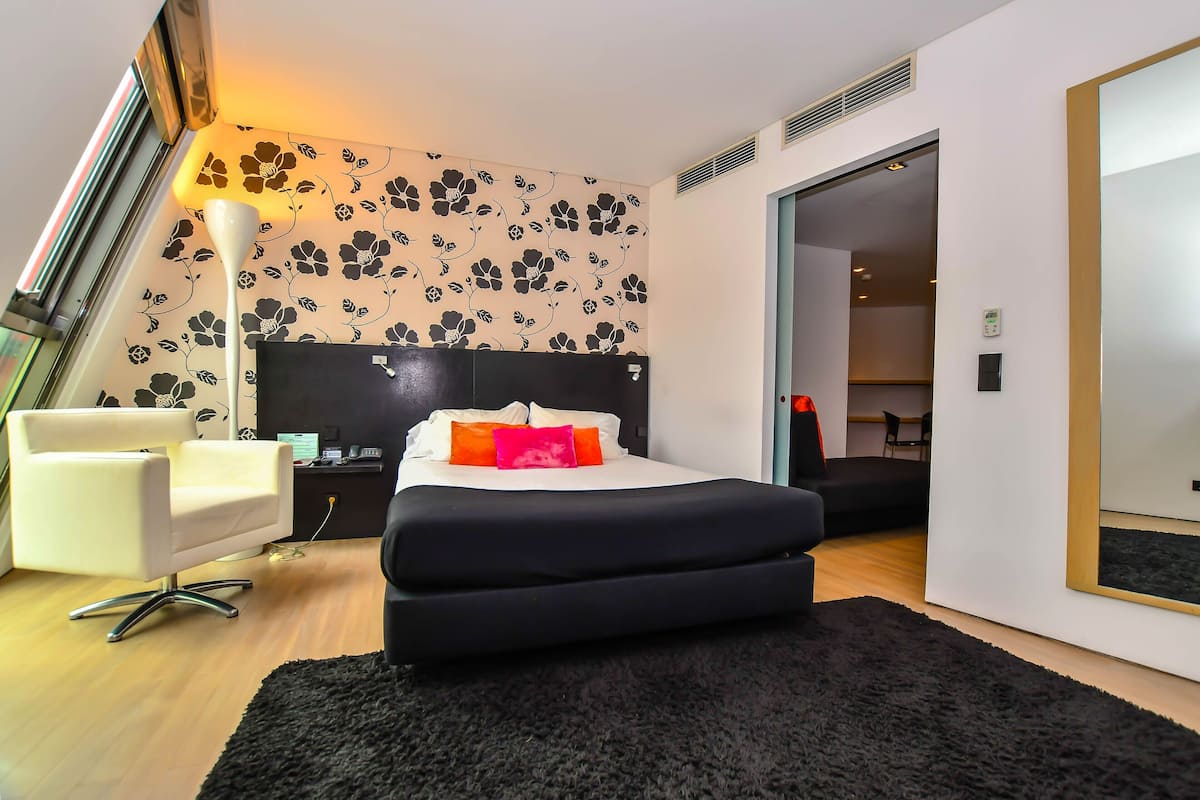 Ein modernes Schlafzimmer mit einem schwarzen Bett, einem weißen Stuhl und blumigem Wandpapier.