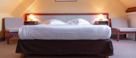 A hotel room with a large bed, two bedside tables with lamps, a headboard, and a framed picture on the wall.