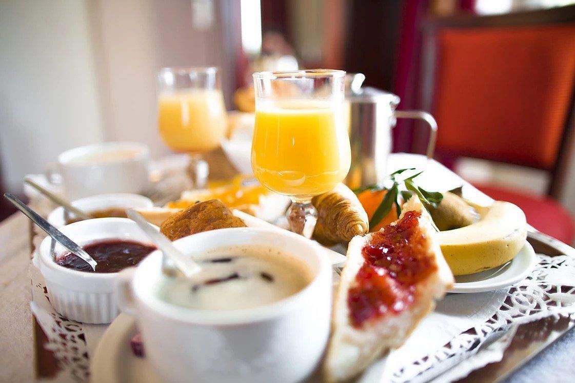 Ein Frühstückswagen mit verschiedenen Speisen und Getränken, darunter Toast, Marmelade und Orangensaft.