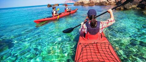 Vista despejada de un kayak sobre aguas tranquilas, con formaciones rocosas al fondo.