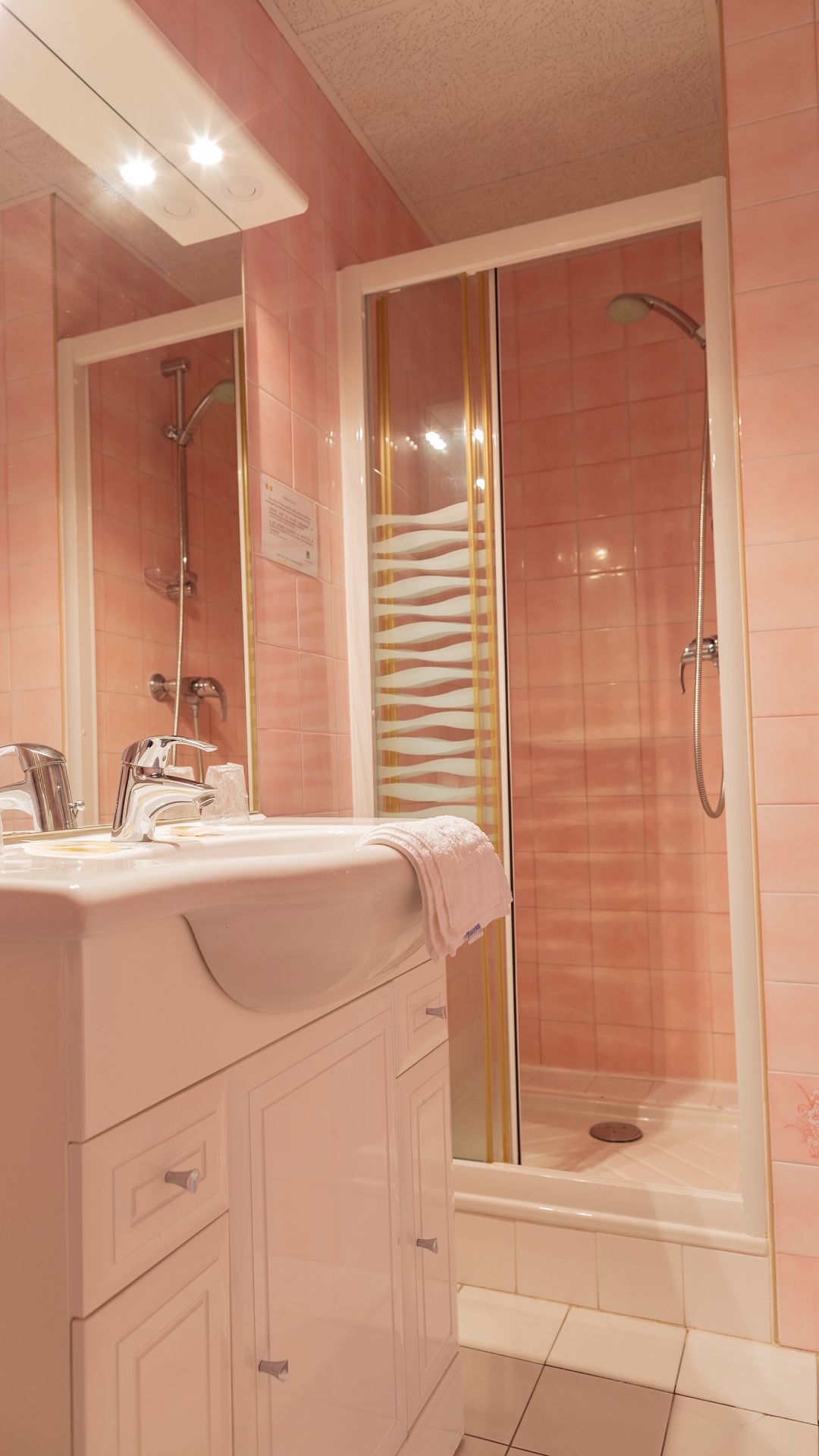 Un baño con ducha, lavamanos y espejo.