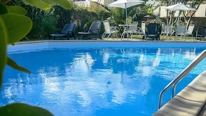 Une piscine d’un bleu éclatant, avec des chaises longues et des parasols.