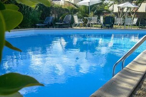Une piscine d’un bleu éclatant, avec des chaises longues et des parasols.