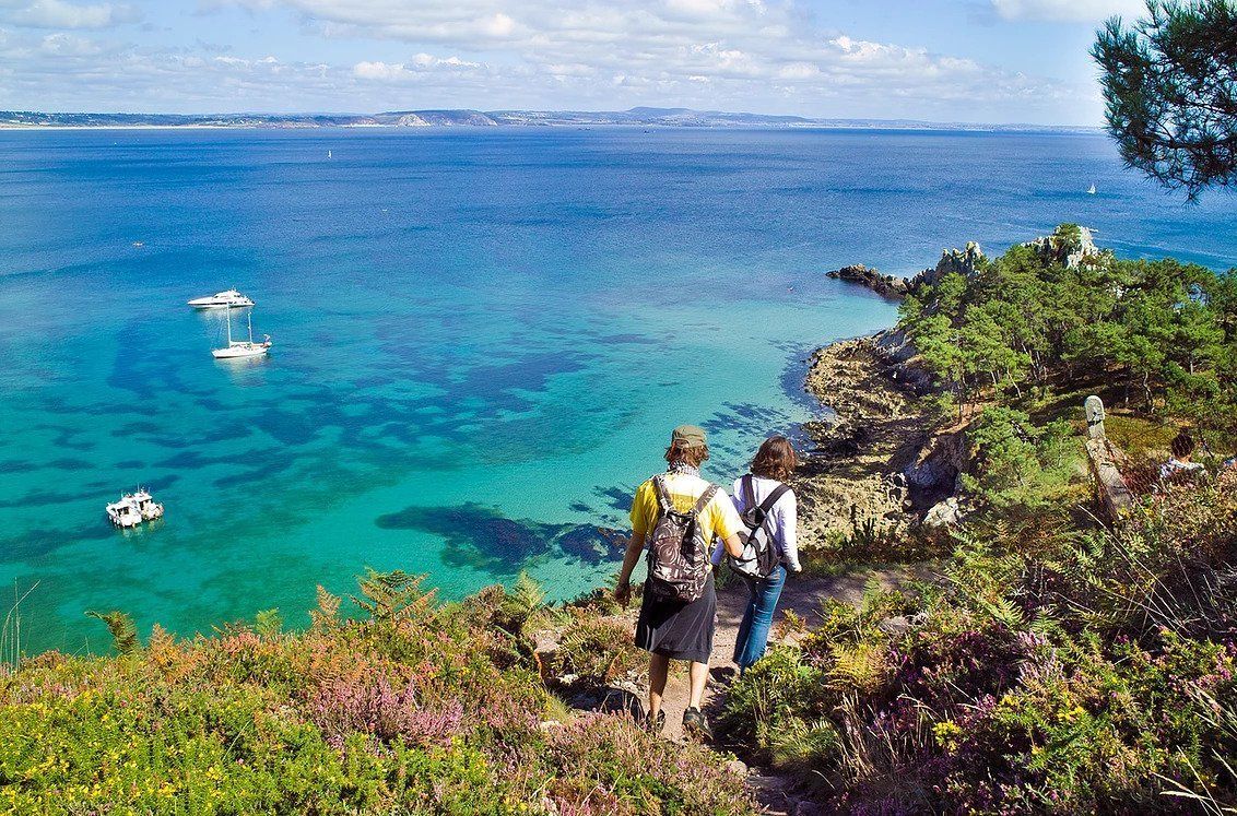 Een kustwandelpad met helder turquoise water en boten.