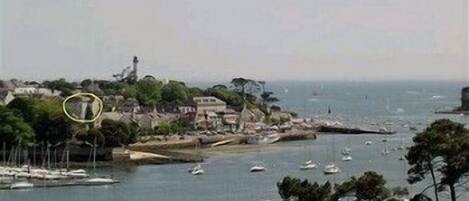 A coastal town with boats docked along the shore and a lighthouse in the distance.