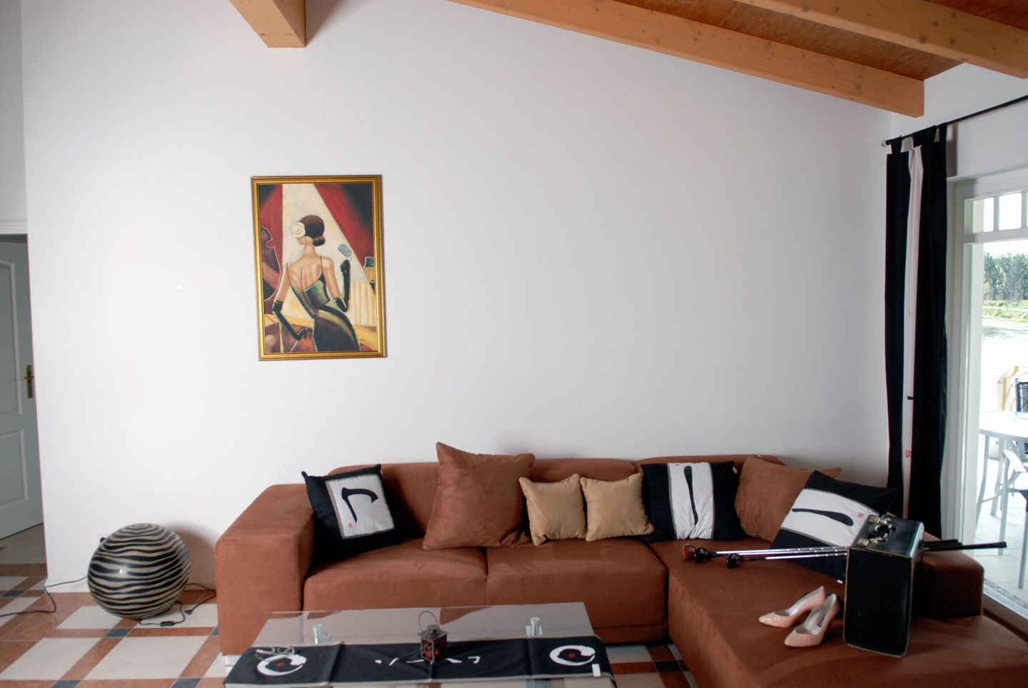 Uma sala de estar com um sofá marrom, uma mesa de centro de vidro e um quadro na parede.