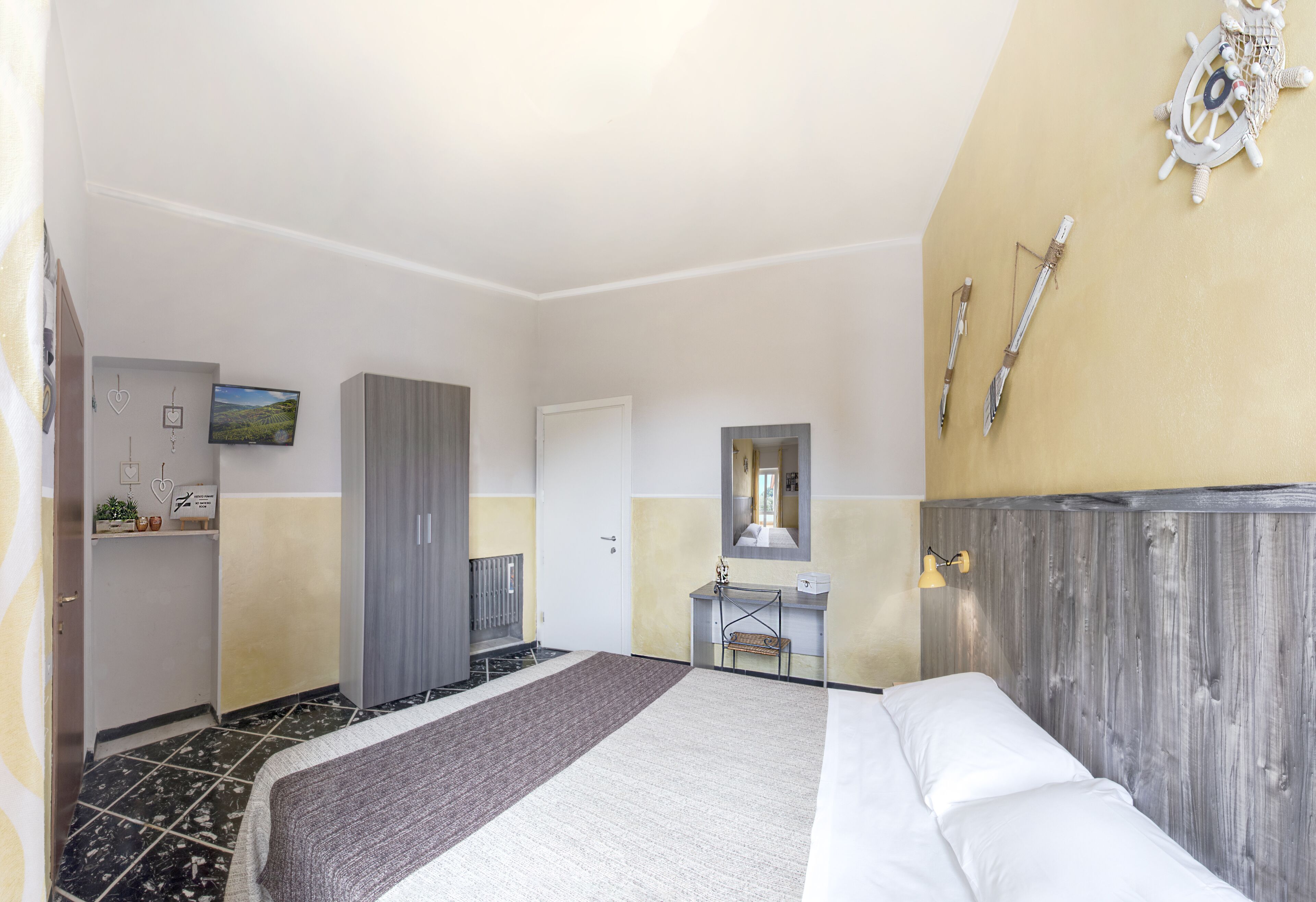 Habitación de hotel con cama, escritorio, espejo y armario.
