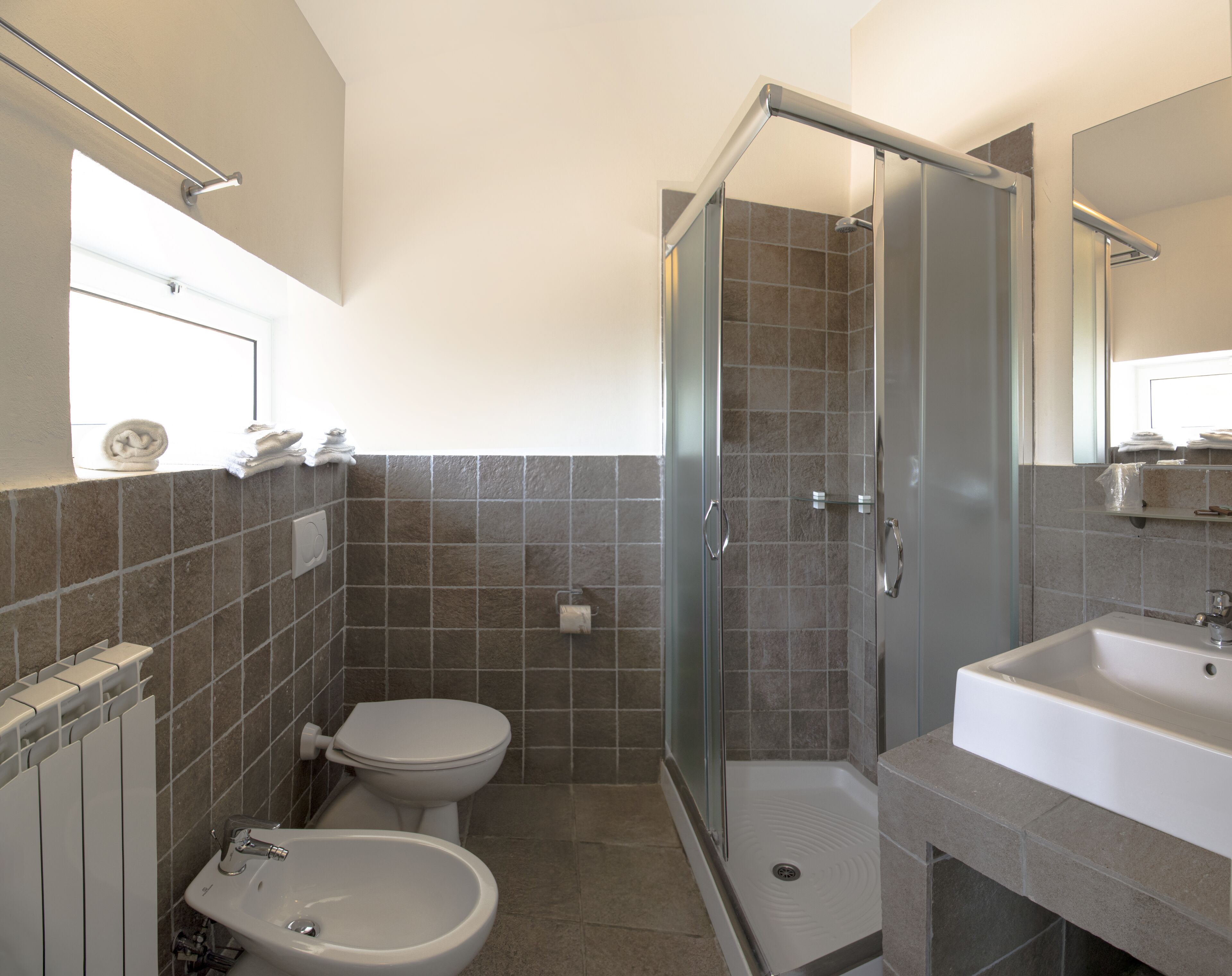 A modern bathroom with a shower, toilet, and sink.