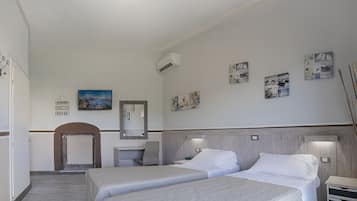 Ein Hotelzimmer mit zwei Betten, einem Schreibtisch, einem Stuhl, einem Spiegel und Wandbildern.