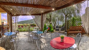 An outdoor patio area with tables and chairs, a wooden bench, and a view of a mountainous landscape. - Albergo Serena (Arcola)