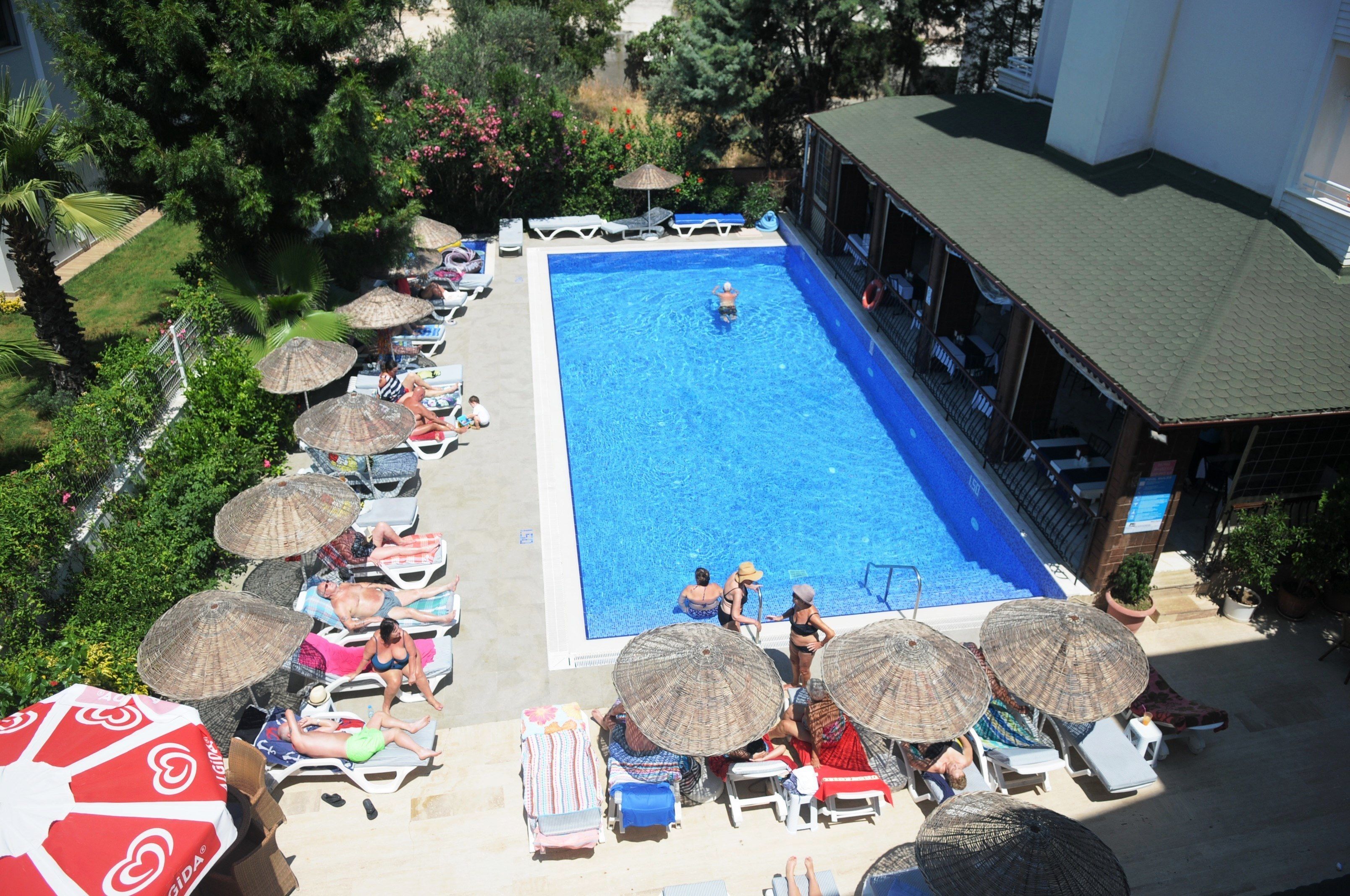Une piscine entourée de verdure, avec des chaises longues et des parasols.