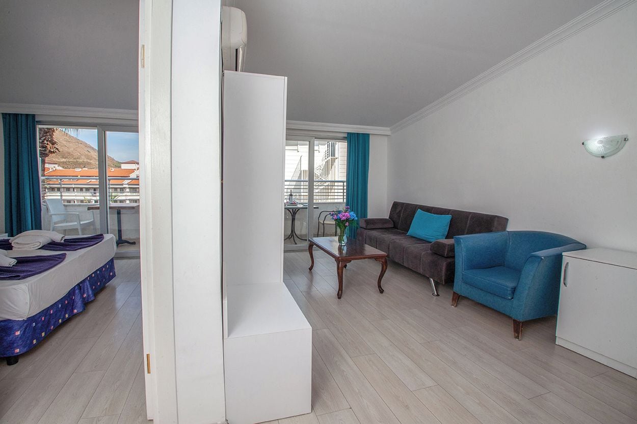 Una habitación de hotel moderna con una cama, un sofá, una mesa de centro y vistas a la ciudad.