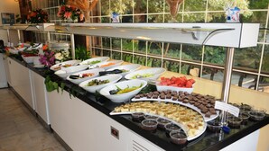 A buffet with various food items and a view of greenery through a window. - Navy Hotel (Marmaris)