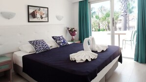 A hotel room with a bed, a nightstand, a wall-mounted lamp, a framed picture, and a view of the outdoors. - Navy Hotel (Marmaris)