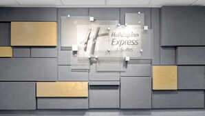 Interior de hotel con diseño moderno, destacando un cartel central de Holiday Inn Express & Suites.