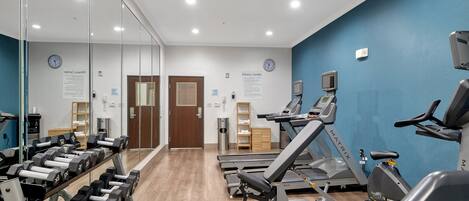 A fitness center with treadmills, dumbbells, and exercise equipment.