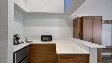 Una cocina moderna con microondas integrado, cafetera y armarios de madera.