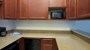 A kitchen with wooden cabinets, a built-in microwave, a coffee maker, and a dishwasher.