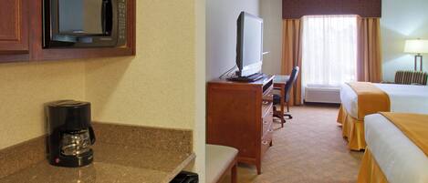 A hotel room with a kitchenette, a bed, a television, and a ceiling fan.