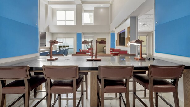 Una amplia sala de conferencias con una larga mesa, múltiples sillas y un diseño moderno en el techo.