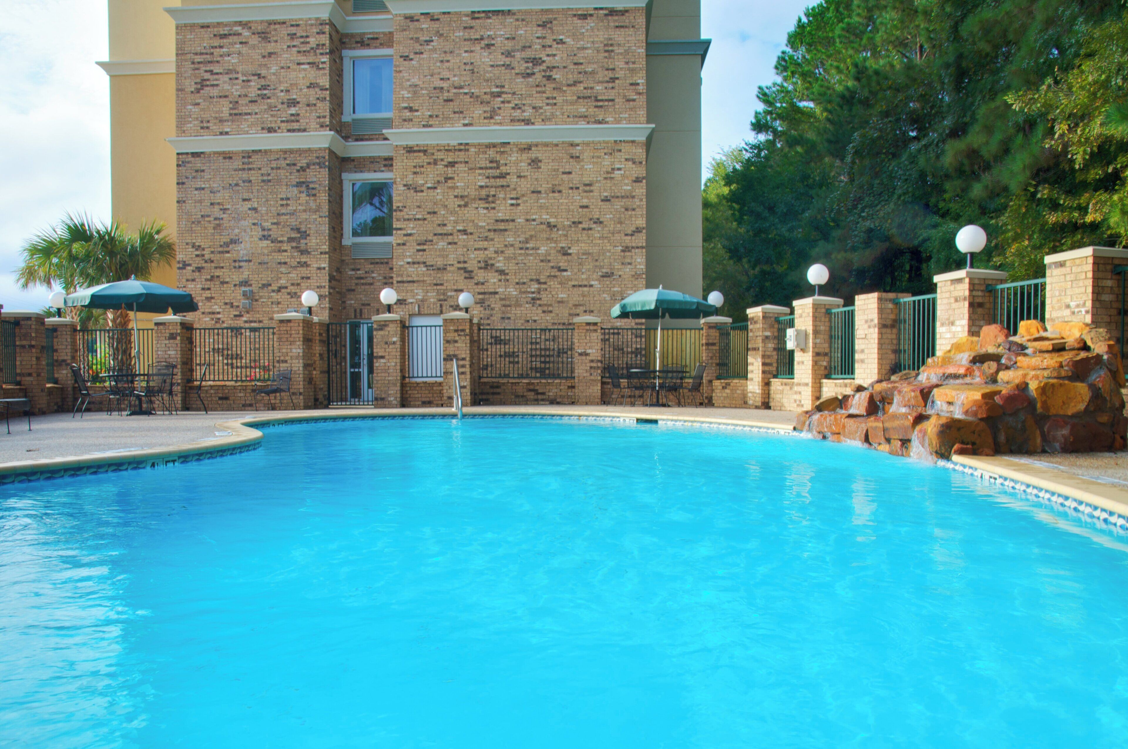 Una piscina con un edificio de ladrillo al fondo.