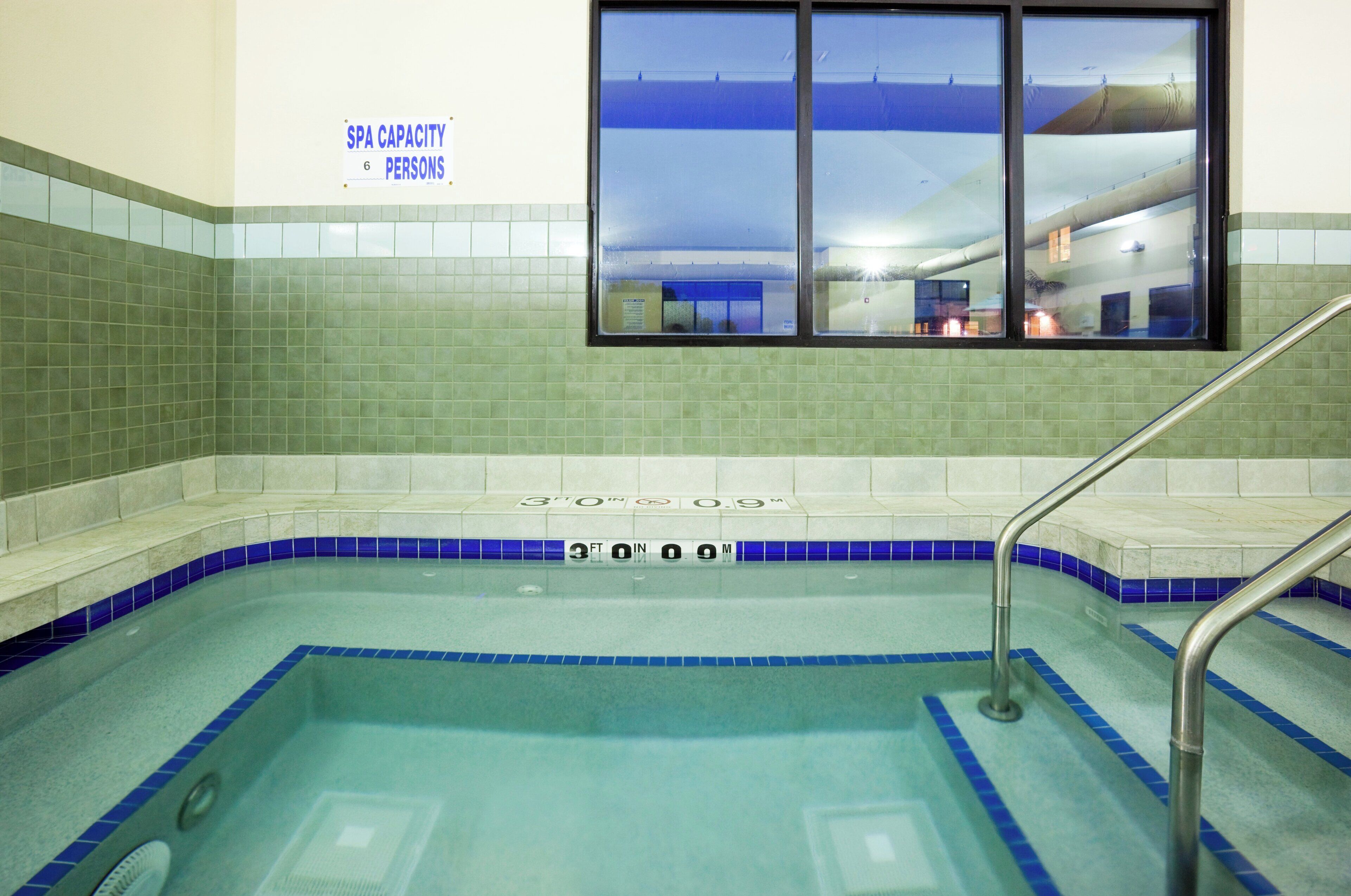 A spa with a capacity of 6 persons, a tiled wall, and a window with a view of the outside.