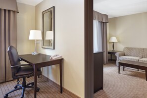 Une chambre d’hôtel équipée d’un bureau, d’un fauteuil de bureau, de deux lampes, d’un canapé et d’un miroir.